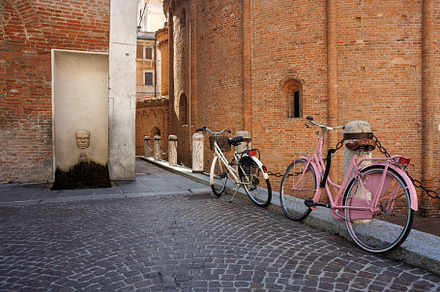 A retro-styled image of two vintage bicycles locked to a railing in Piazza dell, a Transportation Photo by Bepslabor