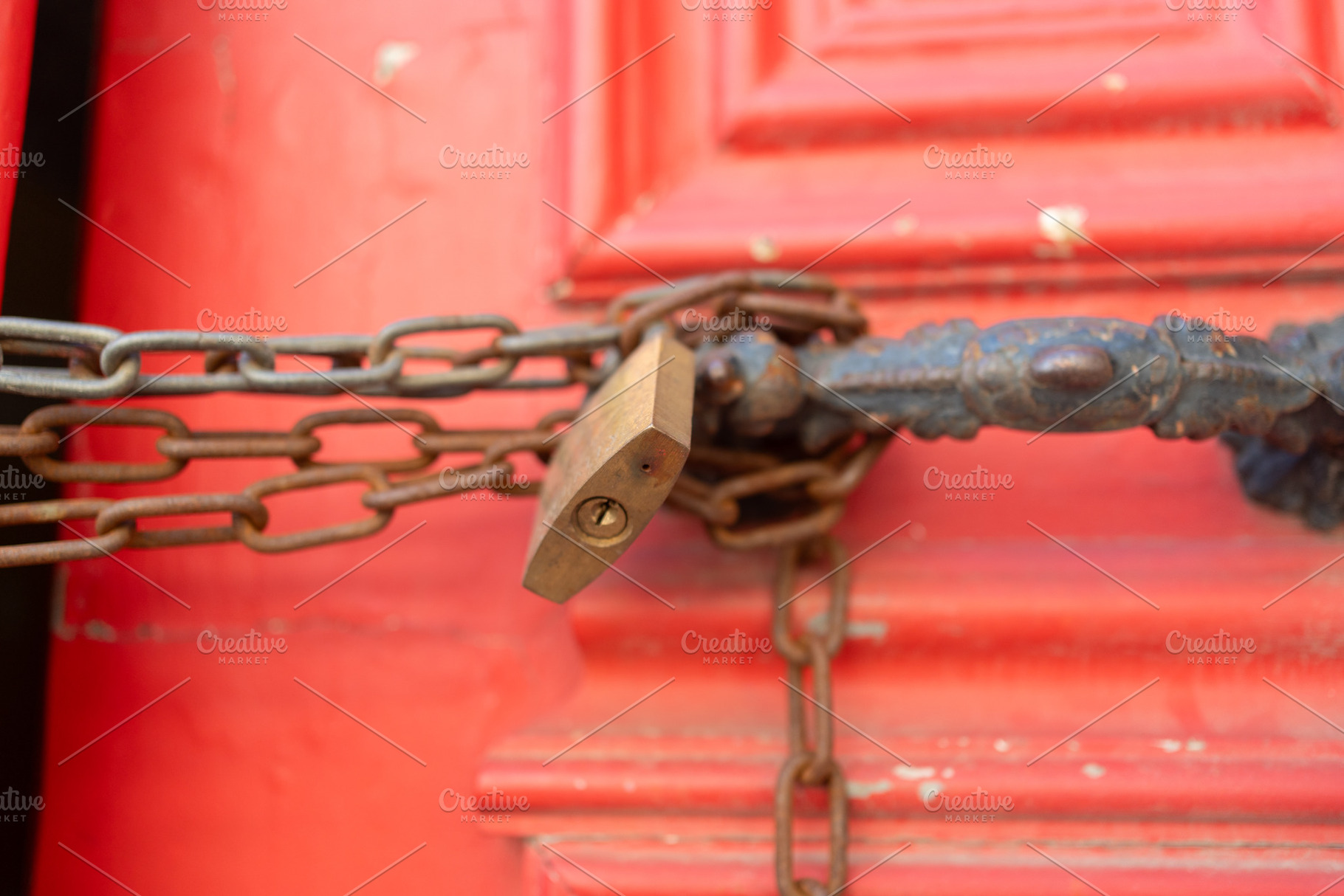 Closeup of metallic chains and locks in handles on red closed doors, a Photo by andreonegin market