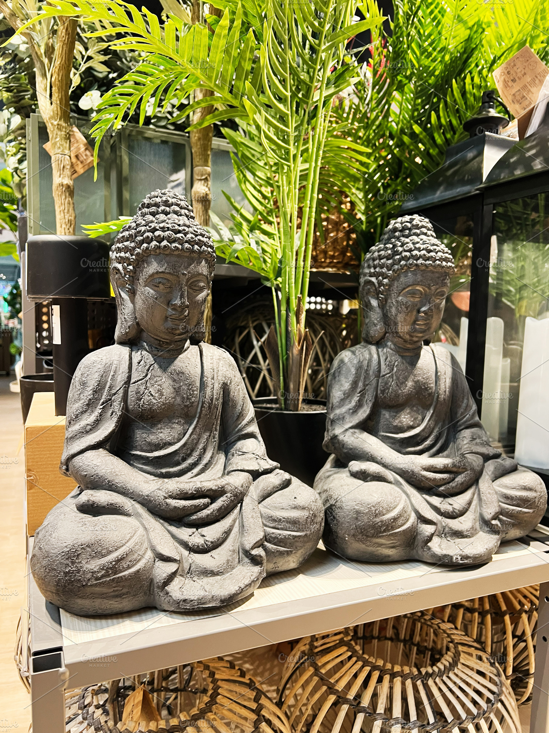 Two stone Buddha statues surrounded by vibrant greenery in a decorative setting, a Photo by AS photostudio