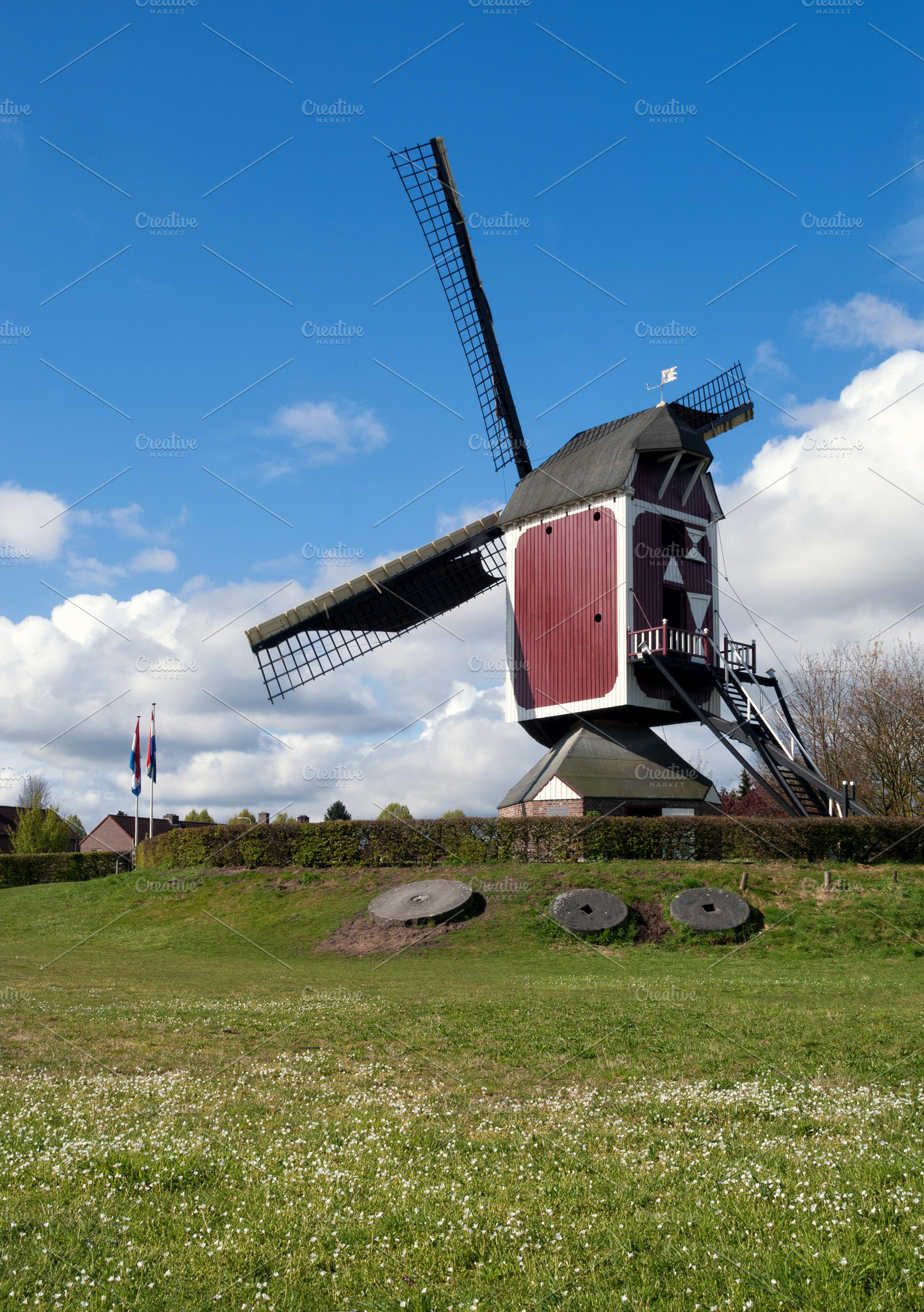 Millstones in a field in front of the Oostenwind windmill, an Architecture Photo by John Stuij Photography