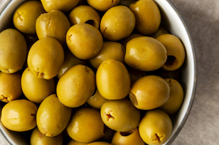 Marinated Green Pitted Olives in a Bowl, top view. Flat lay, ove, a Food & Drink Photo by LiudmylaChuhunova