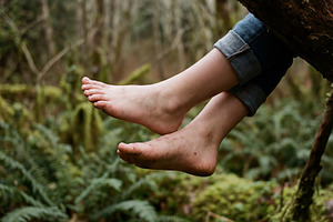 Bare feet dangling from a mossy tree, a Person Photo by Virgo Studio