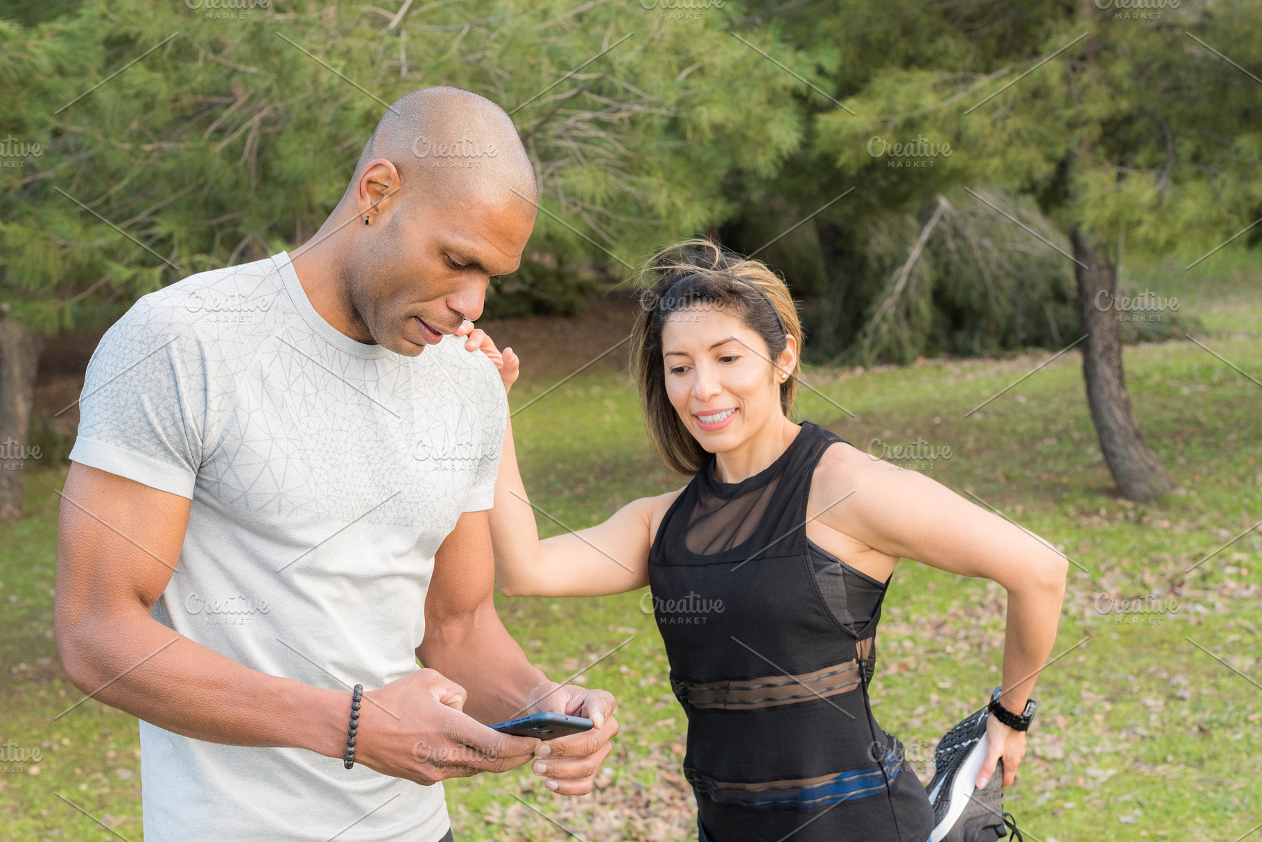 Fitness woman doing stretching leg on her partner who is using cell phone, a Sports & Recreation Photo by Iván Moreno STOCK PHOTO