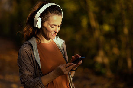 smiling elegant woman in park listening to music, a Sports & Recreation Photo by Alliance Images