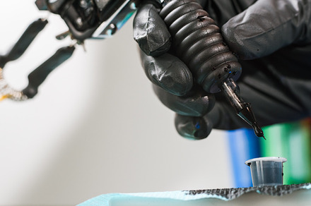 Tattoo artist refilling gun with ink containing background, tattoo, and, a Technology Photo by BodiaPhoto