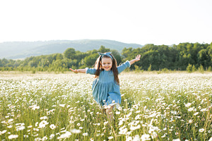Cute child girl in flowers field