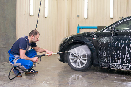 A man washes a black car featuring worker, vehicle, and automobile