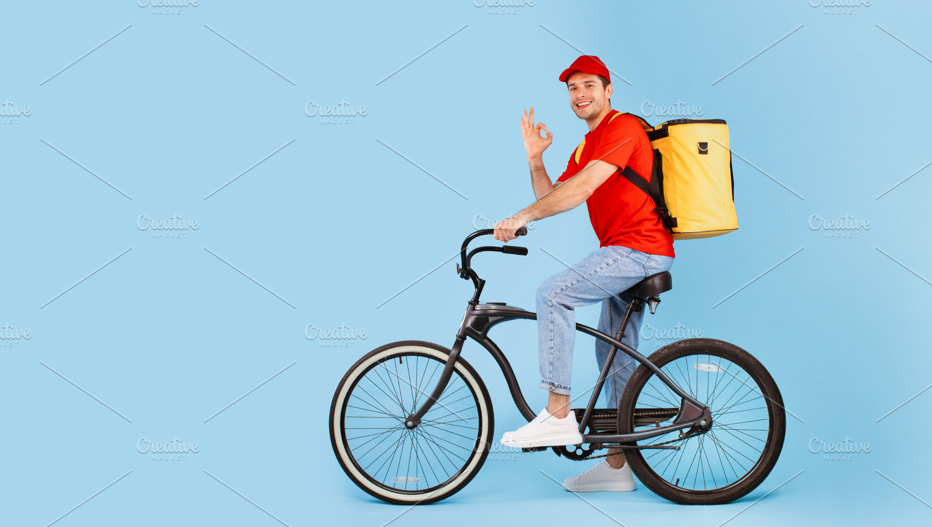 Deliveryman Riding Bike And Gesturing Okay On Blue Background, a Photo by Prostock-Studio
