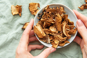 Chef holding bowl of dried mushrooms on green tablecloth, a Food & Drink Photo by Olena Rudo