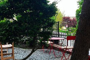Outdoor garden with red furniture surrounded by lush green foliage, a Photo by AS photostudio