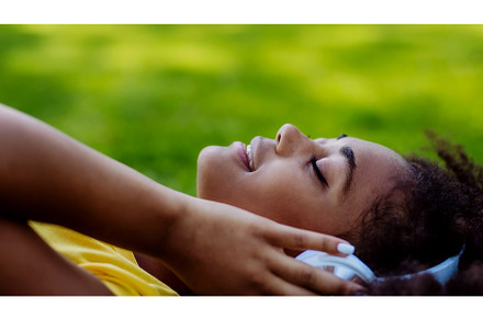 Multiracial girl lying down in grass, a Person Photo by HalfPoint
