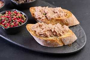Tuna bruschetta on black slate with spices nearby., a Food & Drink Photo by ndanko