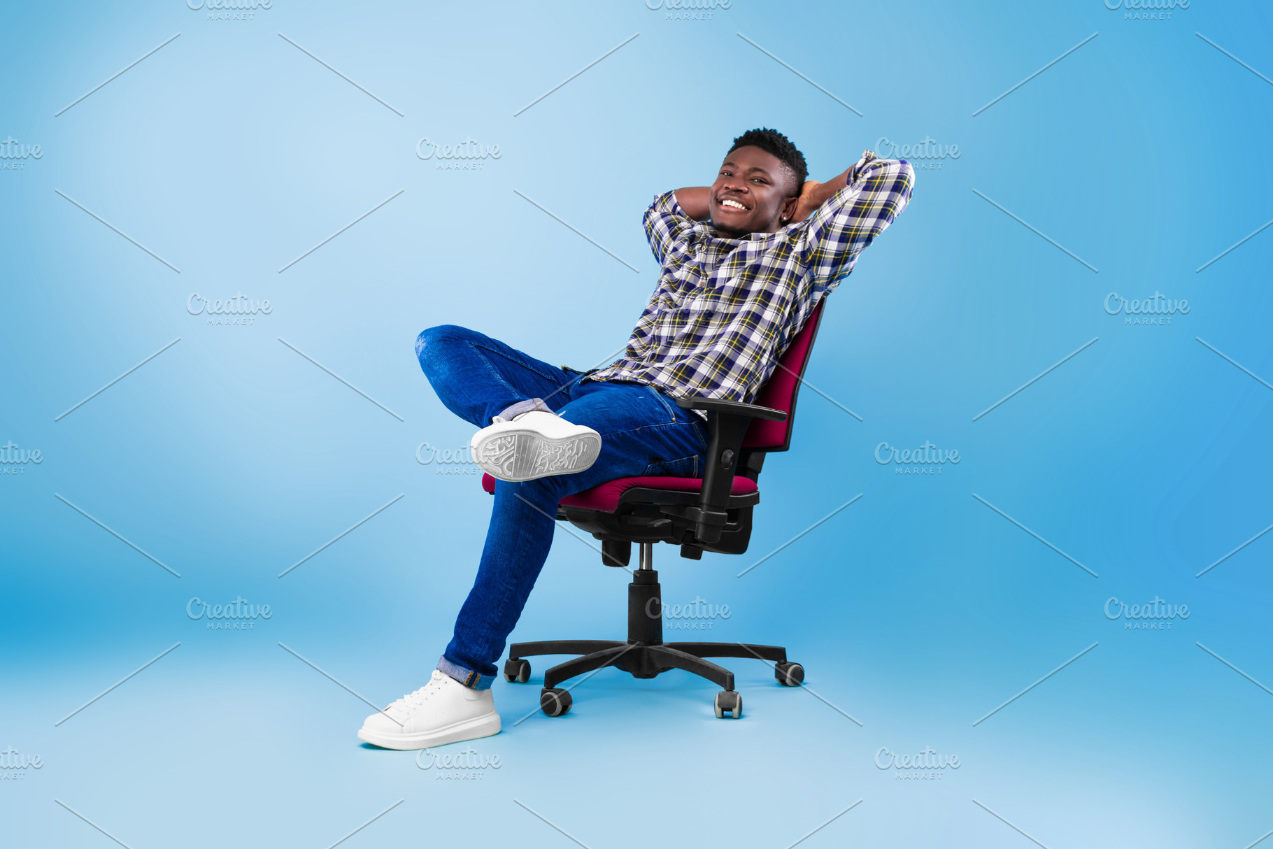 Handsome happy young black man relaxing in chair over blue studio background, f, a Photo by Prostock-Studio