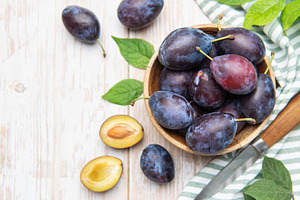 Fresh plums in wooden bowl with knife, a Food & Drink Photo by Olena Rudo