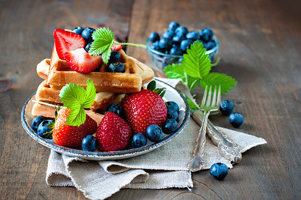 Belgian waffles with berries featuring strawberry, blueberry, and maple