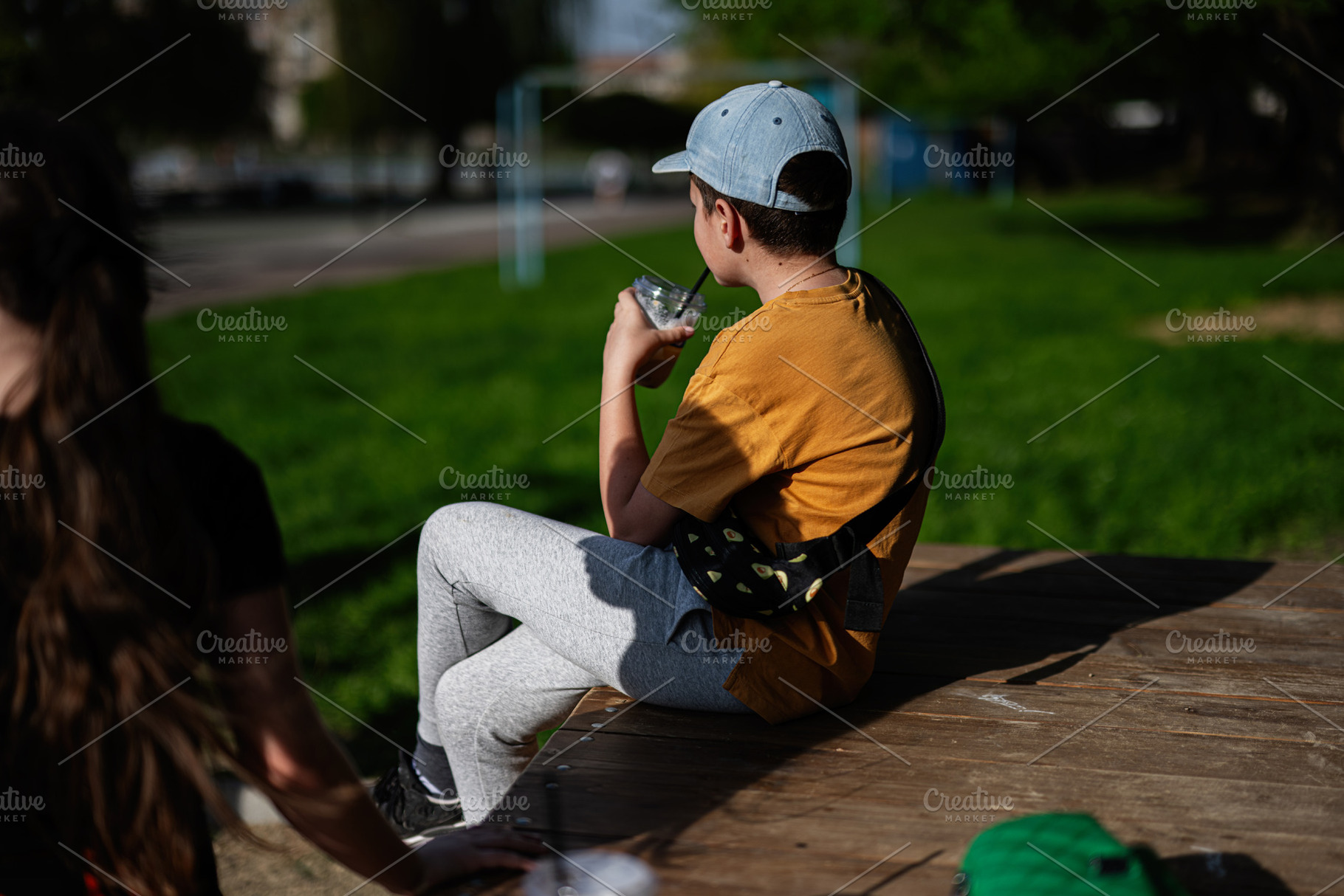 Young boy enjoying a drink while seated outdoors at a sunny park, a Person Photo by AS photostudio
