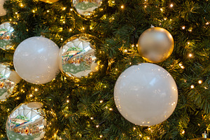 Closeup of shiny golden baubles hanging on illuminated Christmas tree, a Photo by andreonegin market