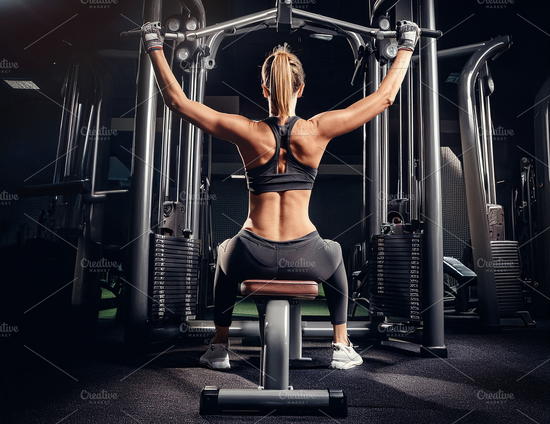 Woman doing back exercises on machine in gym rear view, a Sports & Recreation Photo by Davizro's Market