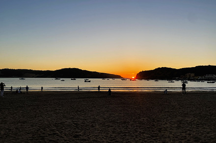 Sunset view over the bay with boats and people on the sandy coast, a Photo by AS photostudio