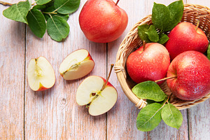 Fresh red apples in basket and sliced on wood, a Food & Drink Photo by Olena Rudo
