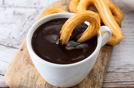 Traditional Spanish churros with hot chocolate breakfast on wooden table, a Food & Drink Photo by etorres69