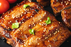 Hot grilled spare ribs from a summer BBQ served on a plate with sauce. Top view, a Food & Drink Photo by Budarinphoto