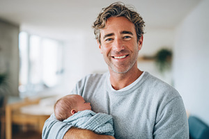 Father holding sleeping newborn in a cozy setting, a Person Photo by AlyaAnd