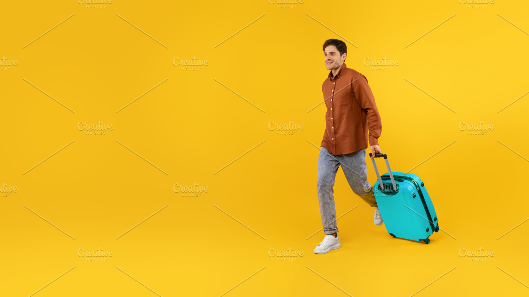 Happy Tourist Guy Walking With Blue Suitcase Over Yellow Background, a Photo by Prostock-Studio