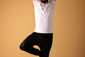 Adult male standing in tree pose on a turquoise mat indoors, aga, a Person Photo by Ales Munt