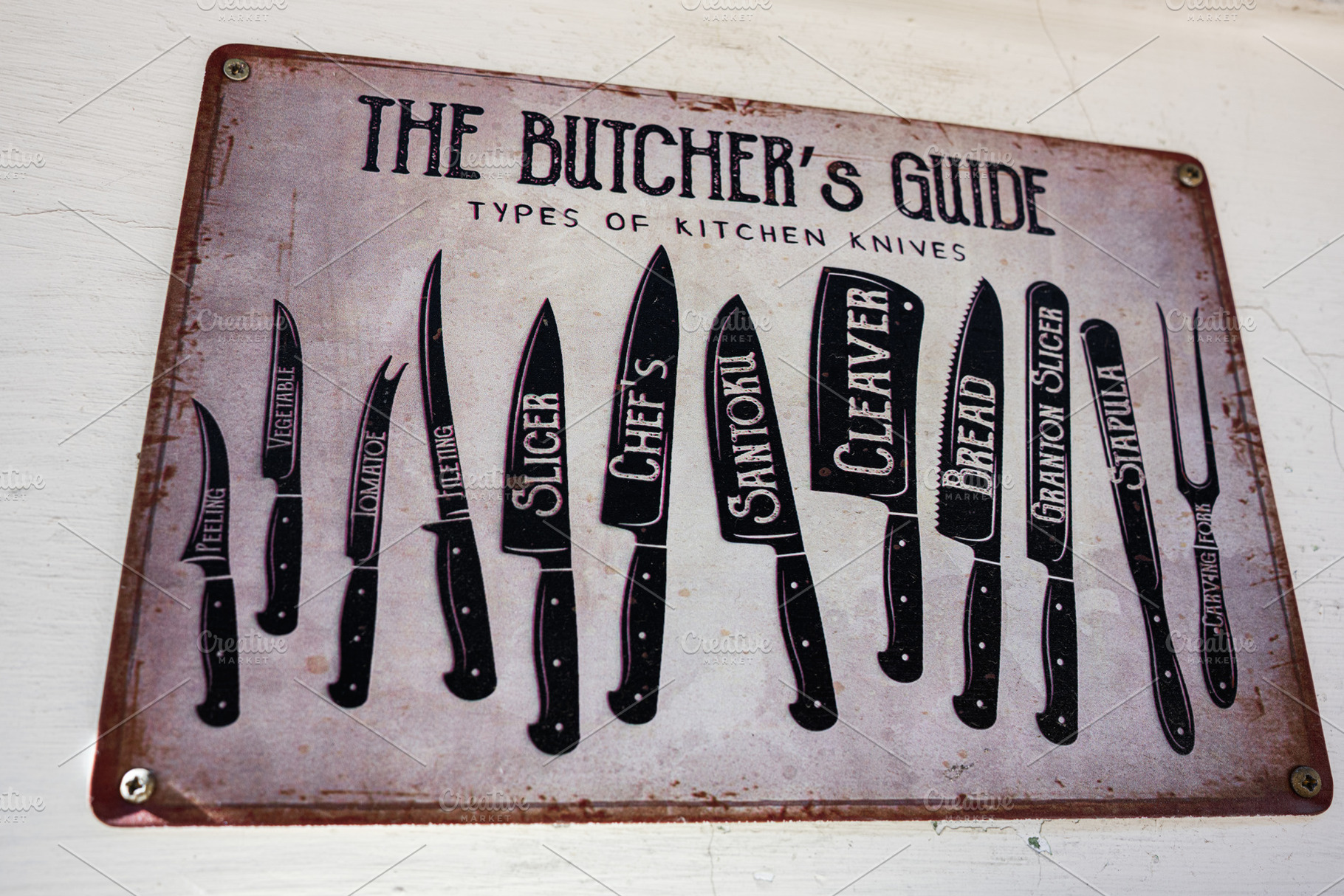 Educational guide showing types of kitchen knives on a rustic metallic sign, a Photo by AS photostudio