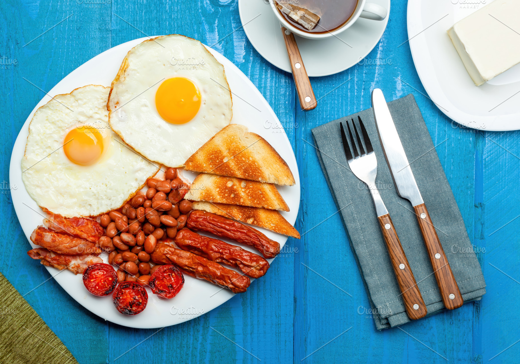 Full english breakfast with fried eggs, sausages, bacon, beans, tomatoes and to, a Food & Drink Photo by Antonio Gravante Market