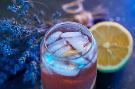 lavender drink with ice and lemon. stone background.