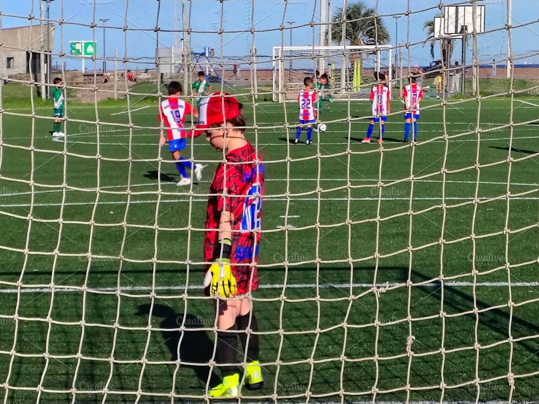 Children playing soccer behind goal net, a Sports & Recreation Photo by DanFLCreativo