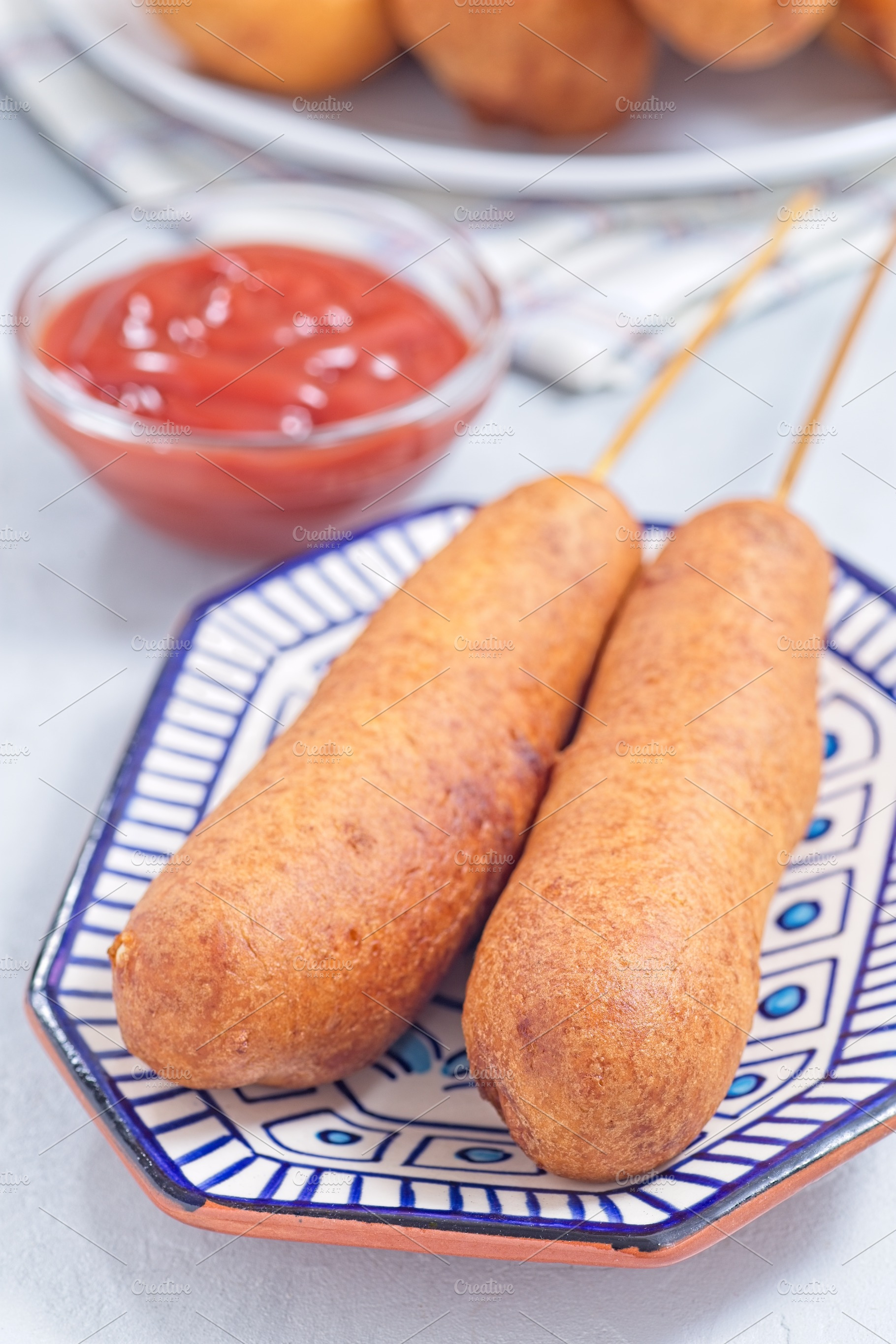 Two corn dogs on white blue plate, served with ketchup, vertical, a Food & Drink Photo by iuliia_n