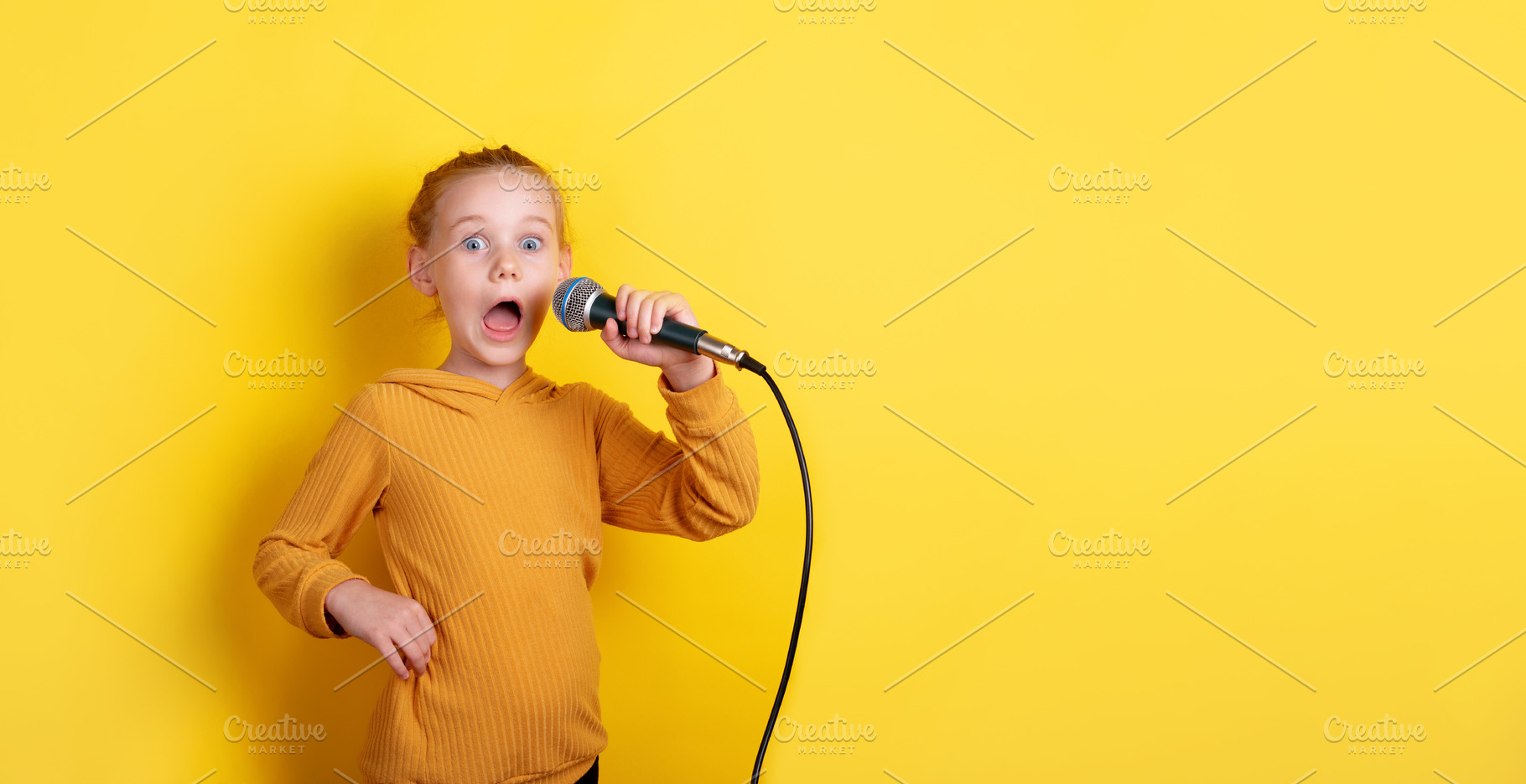 Excited red-haired girl in yellow sweater holding microphone, si, a Person Photo by Ales Munt