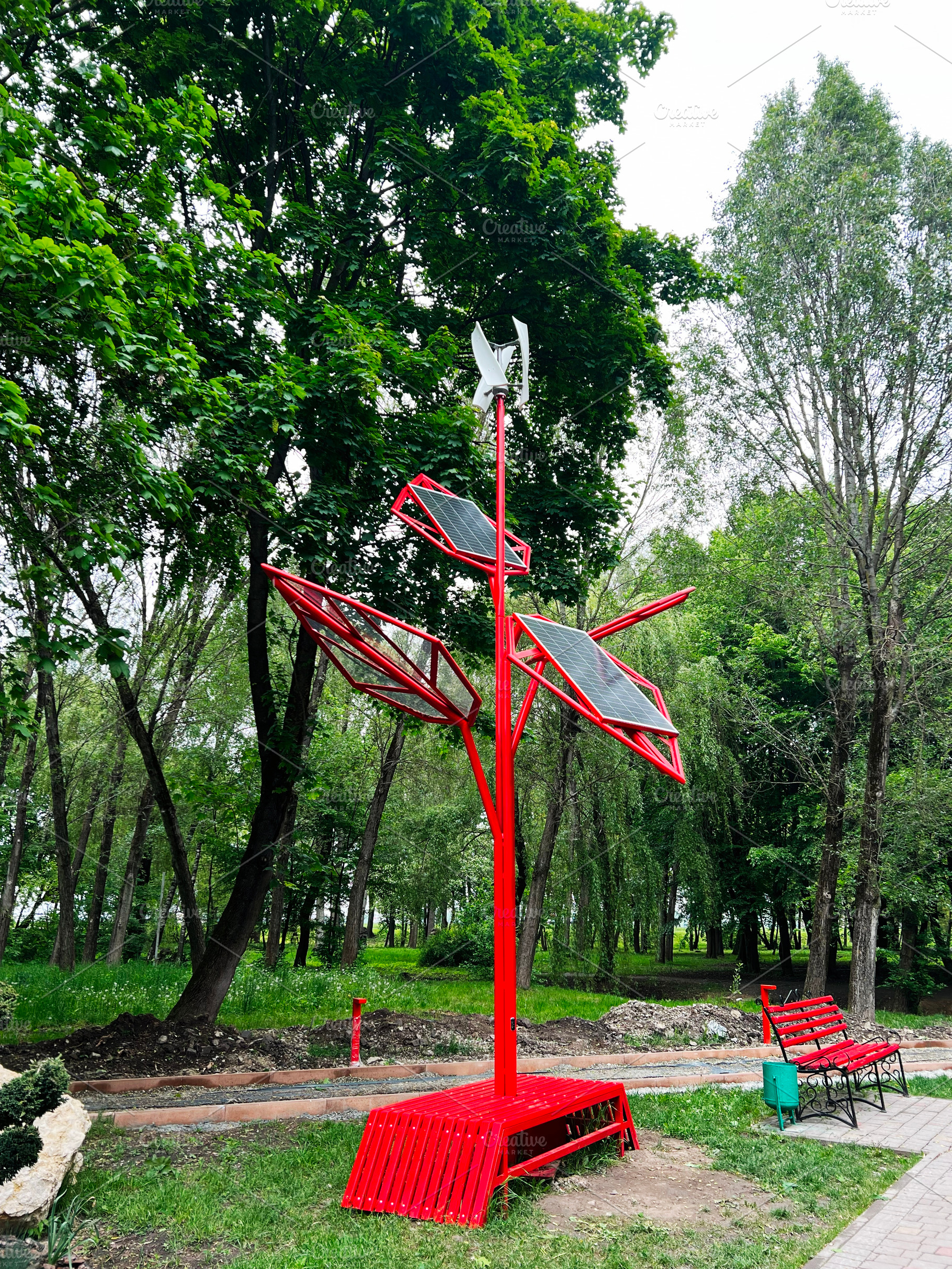Red solar panel sculpture in park surrounded by lush green trees, a Photo by AS photostudio