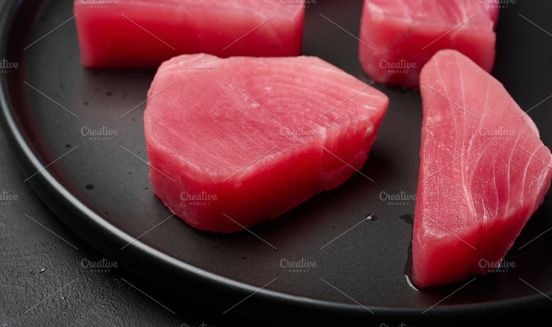 Raw tuna pieces on a black round plate, a Food & Drink Photo by ndanko