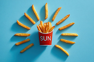 Fries artfully arranged to resemble sun rays around a red cup labeled sun, a Food & Drink Photo by AlyaAnd