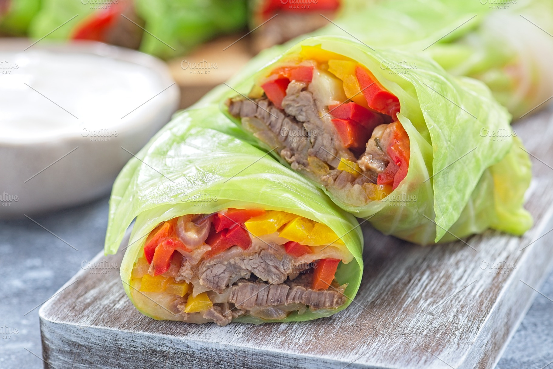 Closeup cut of beef and vegetable cabbage leaves wraps, served with plain yogur, a Food & Drink Photo by iuliia_n
