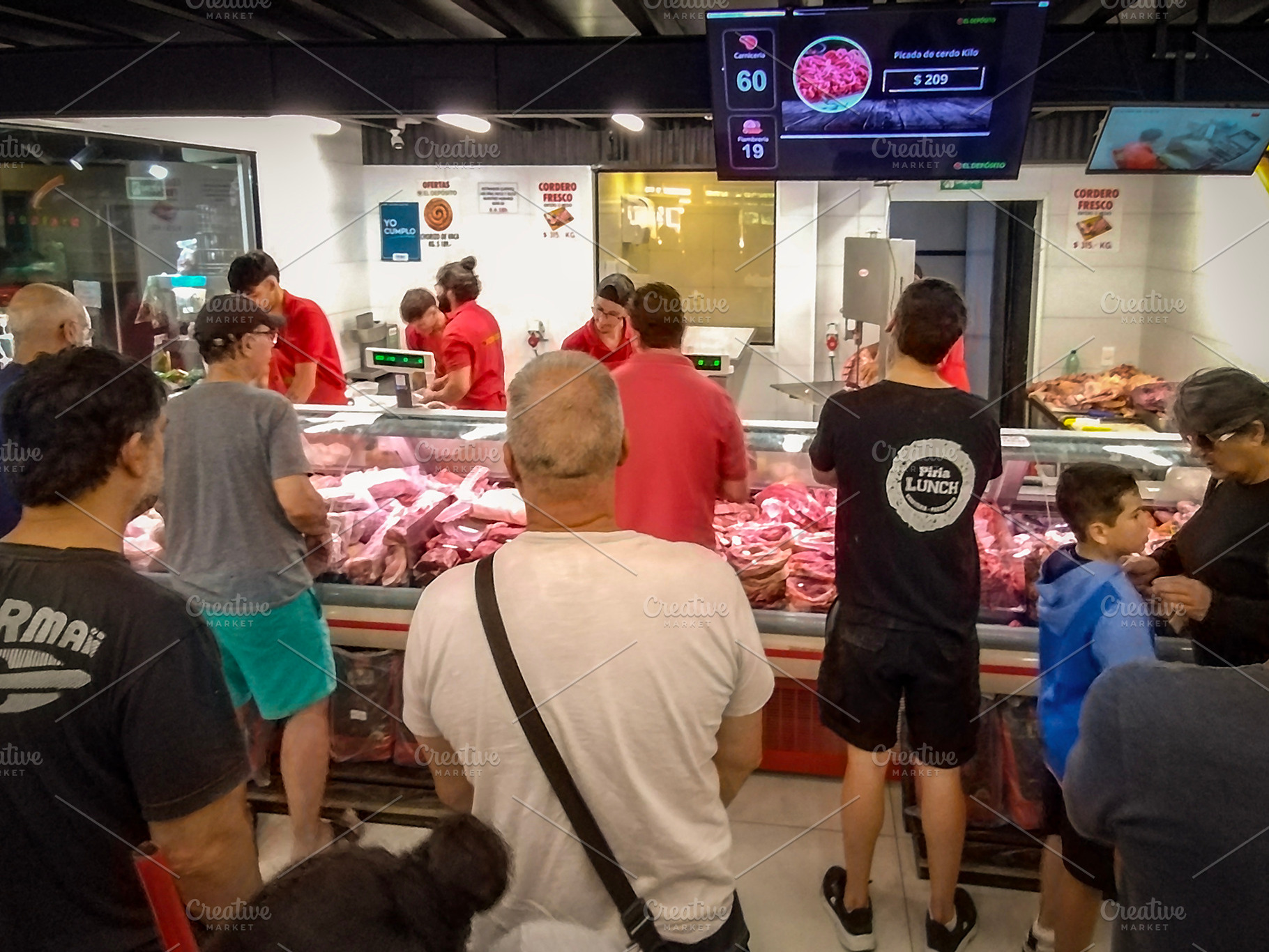 People gathered in front of a counter at a busy indoor meat mark, a Food & Drink Photo by DanFLCreativo