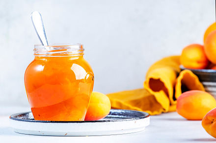 Apricot jam or confiture in glass jar with spoon, fresh fruit on, a Food & Drink Photo by 5PH