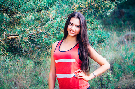 Young beautiful brunette model posing in the sports image of the park against