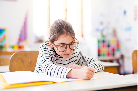 Portrait of cute schoolgirl sitting, a School & Education Photo by HalfPoint