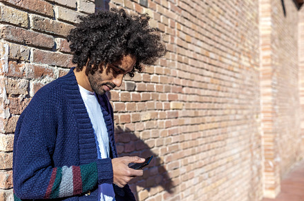 Young afro man using cellphone outdoor, a Person Photo by 2Design