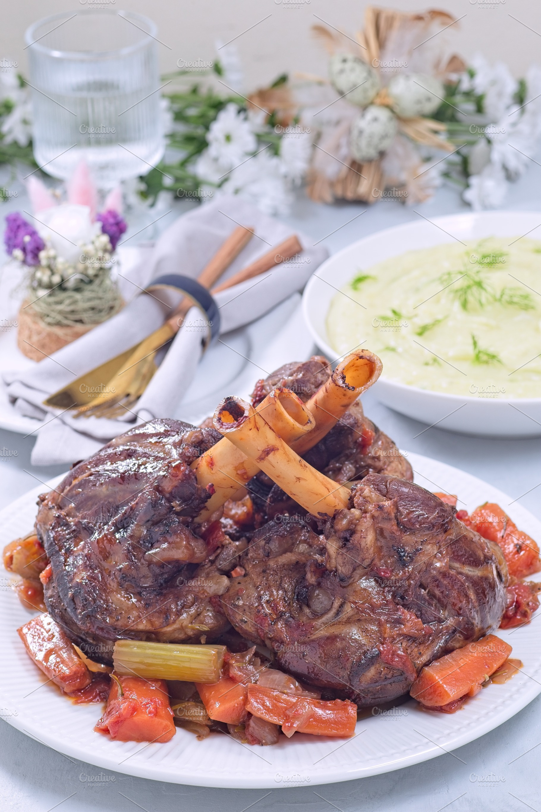 Delicious braised lamb shanks with vegetables on a white plate, vertical, a Food & Drink Photo by iuliia_n
