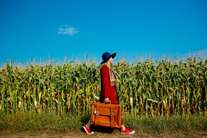 girl with suitcase near cornfield