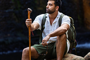 Explorer resting on rocks by a water, a Person Photo by Perpis