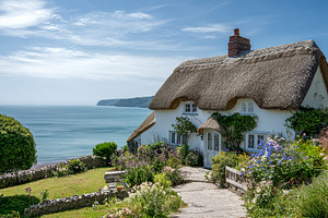 Thatched cottage with a flower garden on a sunny summer day, ove, a Photo by Studio ANNA