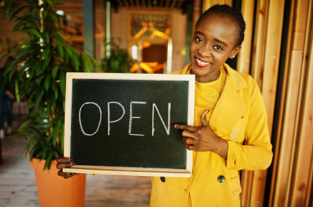African american woman hold open welcome sign board in modern ca, a Business Photo by AS photostudio