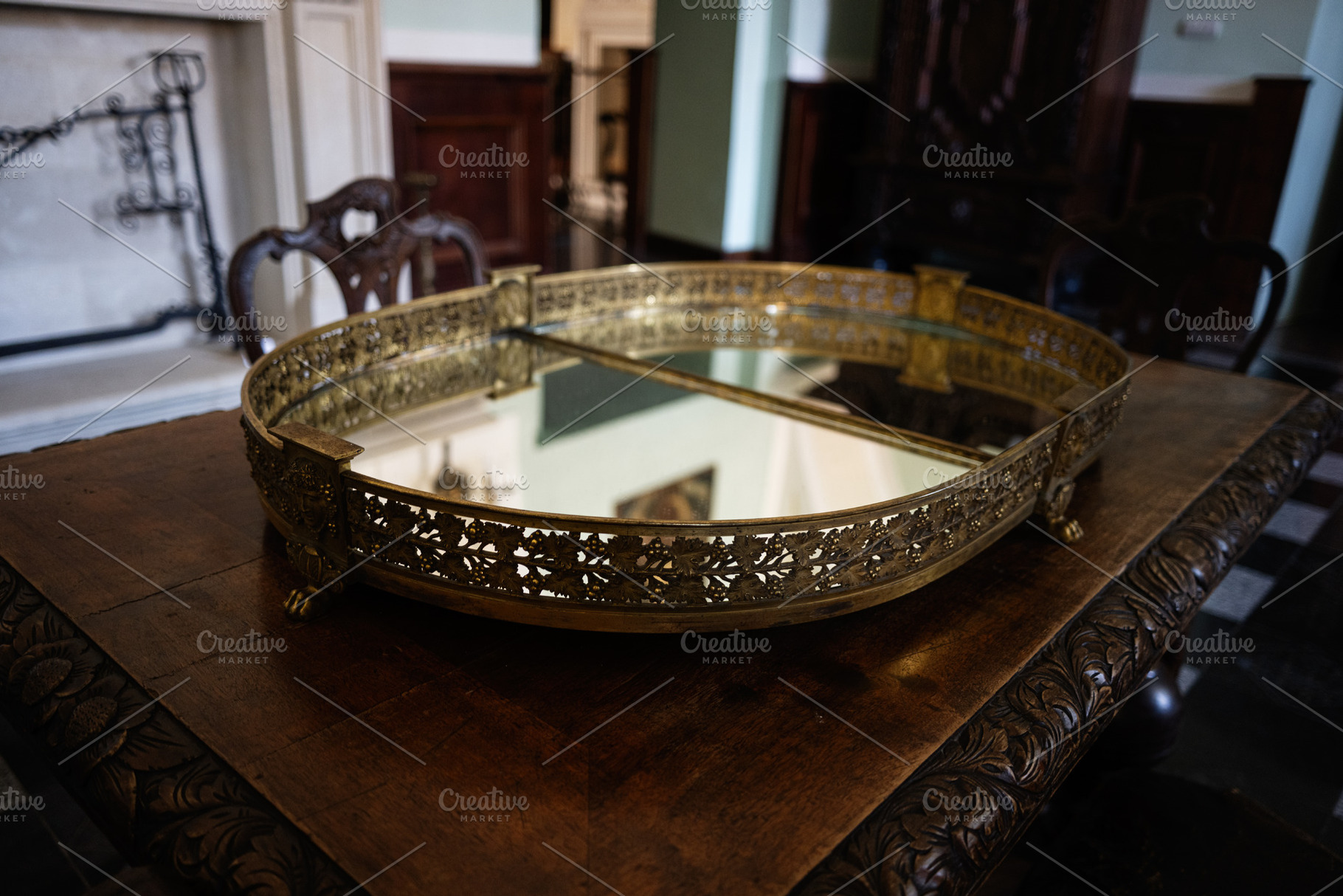 Elegant gold-framed mirror tray placed on carved wooden table in ornate interio, a Photo by AS photostudio